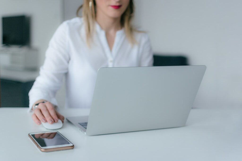 Blonde woman working on her computer with her phone sitting beside it